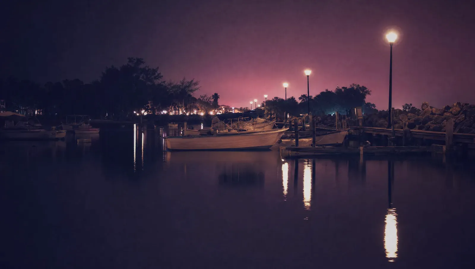 A quiet marina at night with boats reflected in still black water