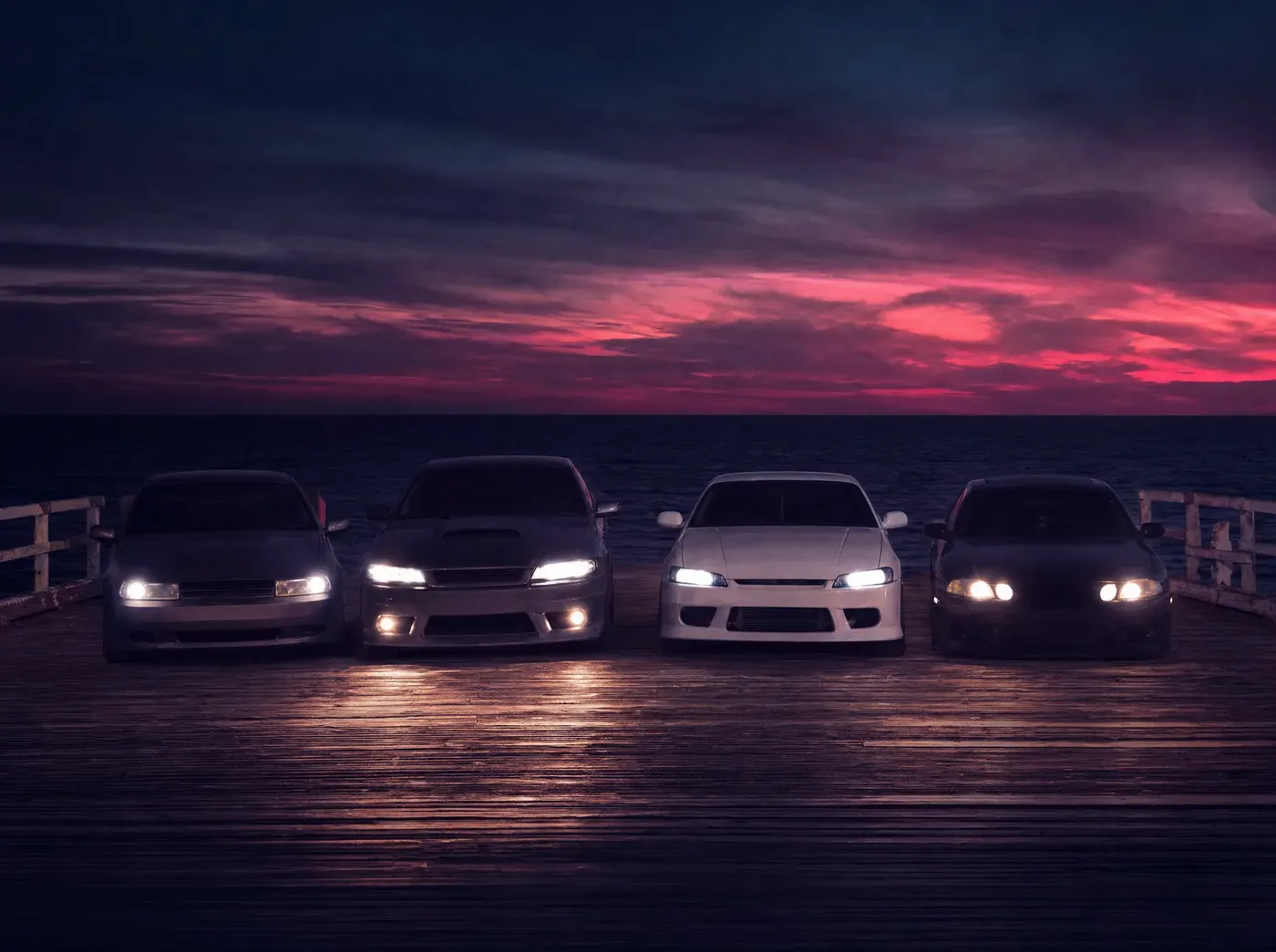 Four cars lined up on a wooden pier at night with headlights on